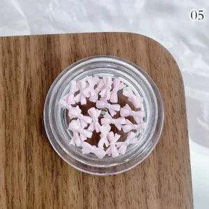 Baby pink nail bow charms featuring pearl accents in a soft pastel hue