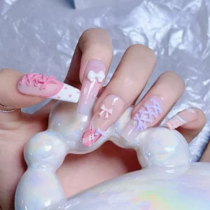 Hand showcasing nail art with ballet lace-up and bow nail charms