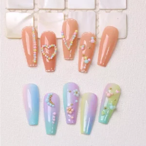 Macaron nail beads arranged into floral and heart patterns on artificial nails