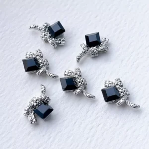 Glossy black square rhinestone nail charms with crystal bow accents