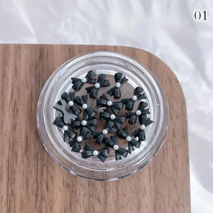 Black pearl bow nail charms with glossy finish in a clear round pot