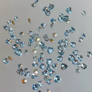Blue heart nail crystals with reflective coating scattered on neutral background