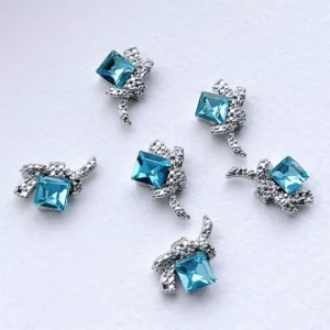 Blue square rhinestone nail charms with silver bows on white background
