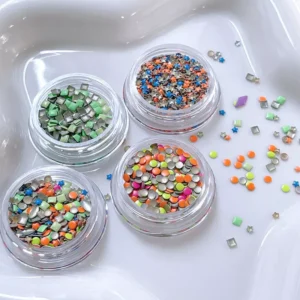 Colorful mixed shape nail decorations scattered beside clear jars