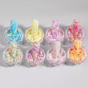 Eight open jars of chunky rainbow nail glitter flakes with swatch sticks