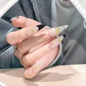 Gold bow nail art shown on pointed transparent nail tips