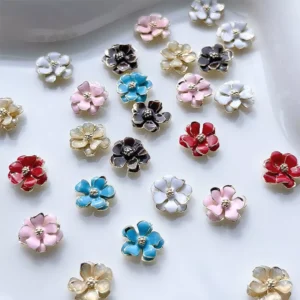 Soft pink, blue, red, and white 3D floral nail charms scattered on white paper
