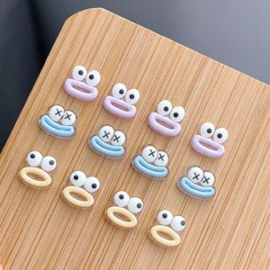 3D cartoon monster nail charms in multiple colors on wood surface