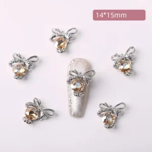 Champagne crystal bow nail charm placed on silver glitter nail design
