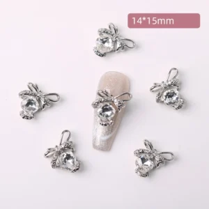 Clear crystal bow nail charm with silver sparkle, shown on shimmering beige nail