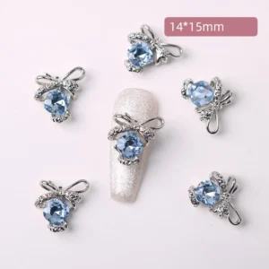 Light blue crystal nail charms shaped like bows shown on silver nails