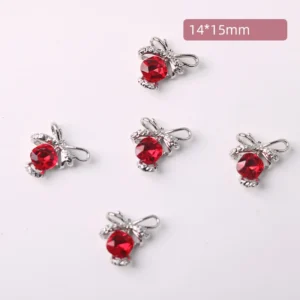 Bright red crystal nail embellishments shaped like bows on white surface