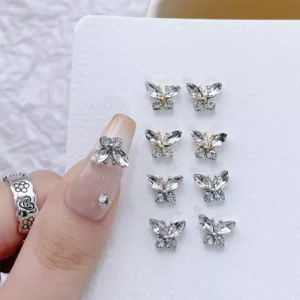 Nude nails with crystal butterfly nail charms and floral ring detail