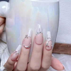 Butterfly nail charms on glossy white nails holding iridescent mug