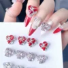 Glam red and pink Crystal Heart Bow Nail Charms with rhinestones on almond-shaped nails
