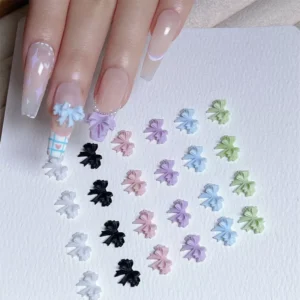 Hand with pastel nail art using resin 3D bow charms next to full color assortment