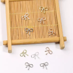 Close-up of alloy bow nail charms on bamboo tray in metallic finishes