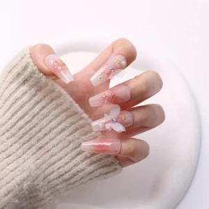 Hand model with sheer pink nails and fantasy butterfly nail charms