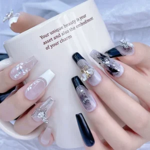 Model holding mug, showing full nail set with butterfly rhinestone charms