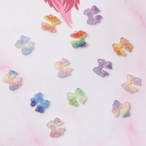 Colorful embossed rainbow bow nail charms spread on white background