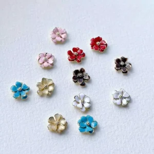 Metal flower nail charms displayed in a ceramic tray under natural light