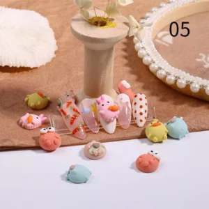 Cartoon pig, crab, and duck charms shown with carrot-themed nails