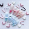 French lace edge nail charms applied to pastel-themed manicure tips with heart and bow details