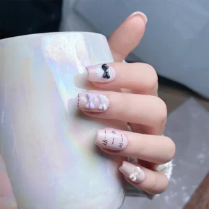 Close-up of hand holding iridescent mug with nails decorated in glossy 3D pearl bows