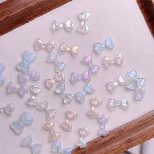 Assorted pastel iridescent bow nail charms on soft background