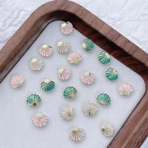 Mixed pastel shell nail decorations in gold-edged alloy finish on a display tray