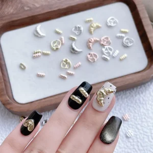 Close-up of gold metal nail charms applied to black and white nail designs