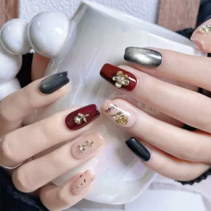 Close-up of hands with Golden Rose Nail Charms applied over glossy red, black, and nude polish