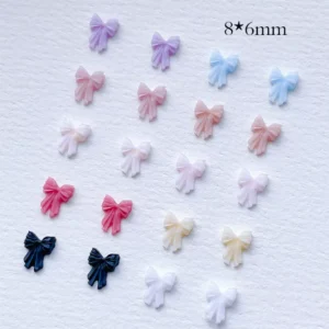 Fan-shaped display of 8×6mm 3D Ribbon Bow Nail Charms in various shades