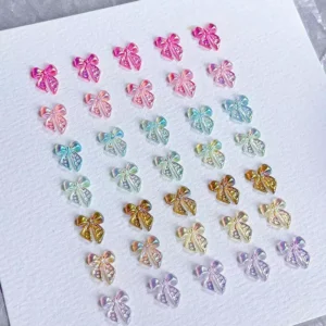 Gradient bow-shaped resin nail charms in pink, gold, and purple tones