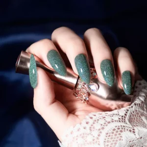 Model holding polish bottle with green crystal glitter manicure