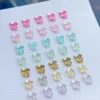 Iridescent bow nail charms in gradient colors arranged on white background