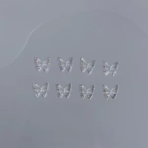 Mixed iridescent and silver butterfly nail charms on translucent board
