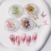 Iridescent butterfly nail charms in gold glitter jars with floral nail art