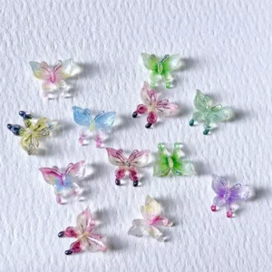 Mixed iridescent butterfly charms in pastel and transparent hues arranged on paper