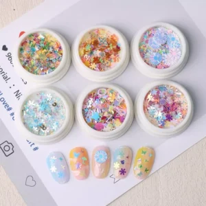 Colorful iridescent nail glitter in plastic jars with flower and daisy shapes, next to pastel nail art samples