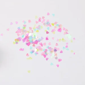 Scattered iridescent heart-shaped nail sequins in multicolor pastel tones