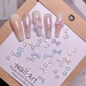 Pink and white press-on nails with applied iridescent bow nail charms