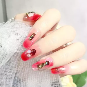 Nail art with iridescent resin gemstones and embellishments on pink gradient base