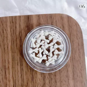 Ivory cream bow nail charms with pearl accents in a translucent resin