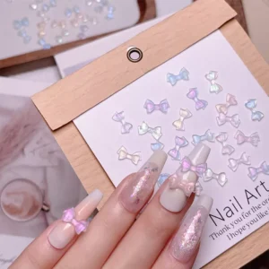 Close-up of nails with applied iridescent bow nail charms and display backing