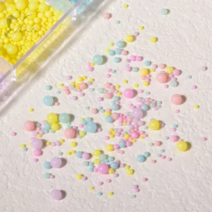 Scattered pastel macaron beads in yellow, pink, and blue tones under direct light