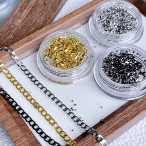 High-shine gold and silver chains laid flat beside corresponding nail beads