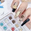 Metal flower nail charms applied on long nude and black acrylic nails with gold edge details