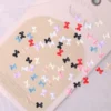 Mixed color mini bow nail charms on a soft pink background – multicolor resin 3D decorations for kawaii nail designs