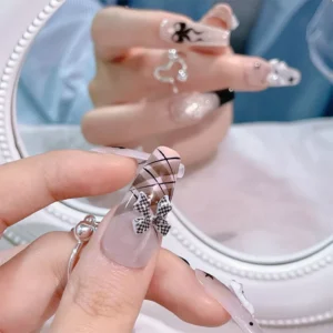 Mirror reflection showcasing retro nail design with plaid bow nail charm